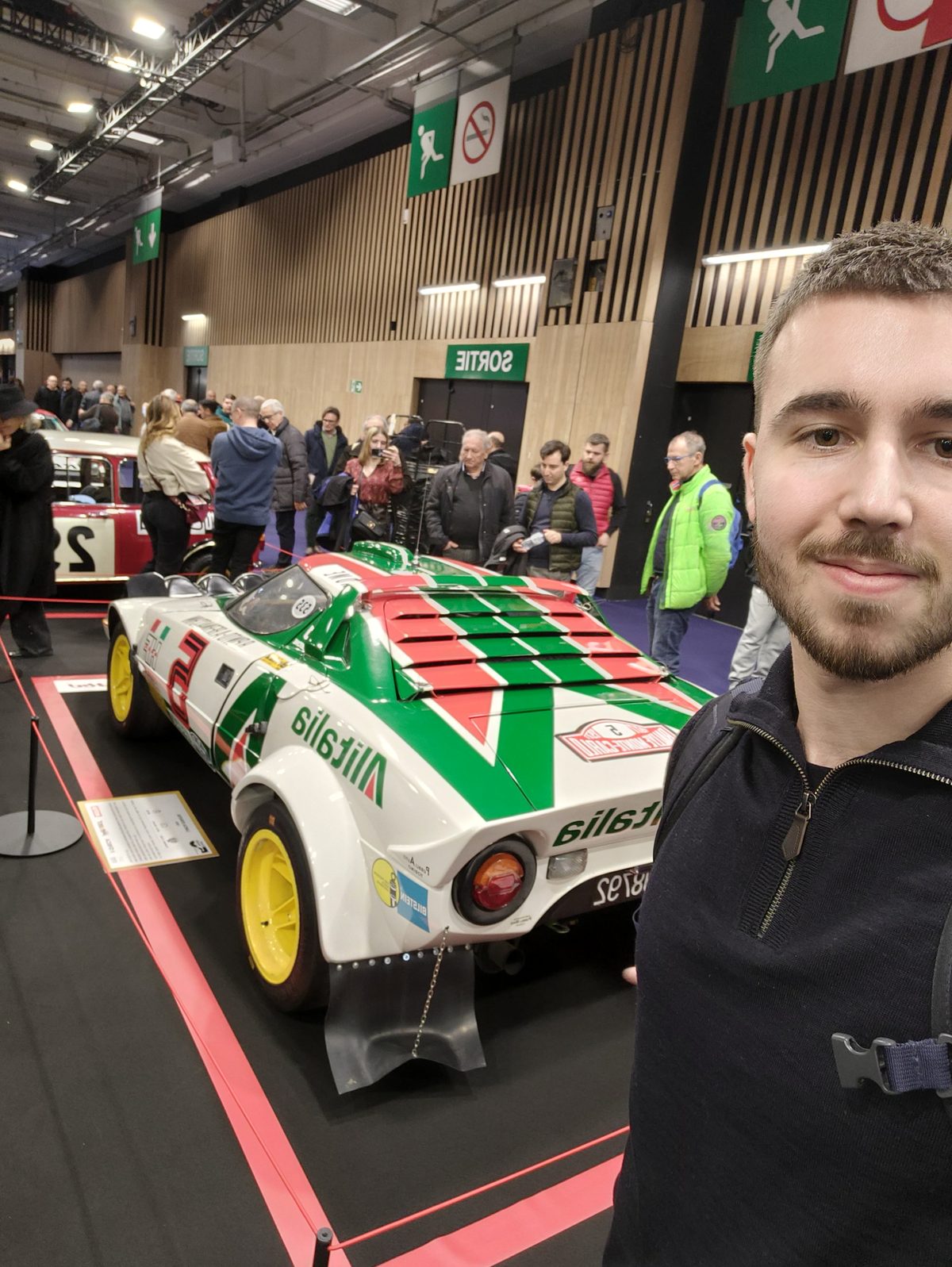 Hugo Fleury au salon Rétromobile devant une Lancia Stratos Alitalia